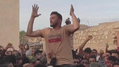 A man holding his hands up in a crowd