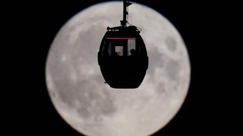Cable car silhouette to moon backdrop