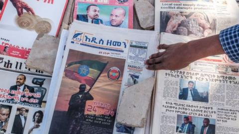 A man points at the cover of a local newspaper in a street stall in a downtown area of the city of Addis Ababa, Ethiopia, on November 3, 2021