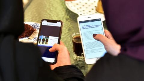 File photo shows women looking at the internet on their mobile phones in Saudi Arabia (27 November 2019)