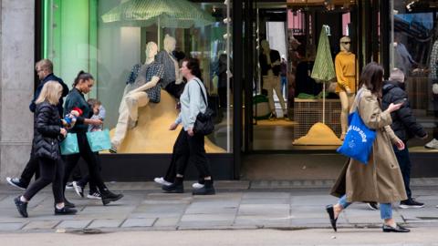 Shoppers walk outside department store in London in April 2024