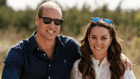 William is wearing sunglasses, jeans and a blue shirt and Kate is wearing a white shirt and jeans. A pair of sunglasses rests on Kate's head.