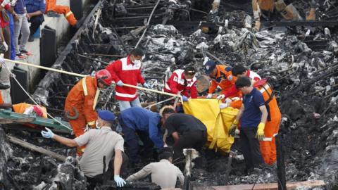 Workers remove bodies of those who died from the ferry on 1 January 2017