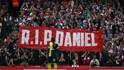 A banner reading 'RIP Daniel' among the crowd at an Arsenal football match