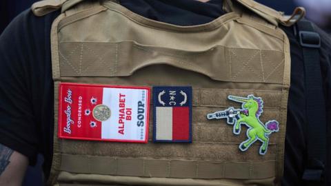 A member of far-right militia the Boogaloo Bois walks next to protesters demonstrating outside Charlotte Mecklenburg Police Department