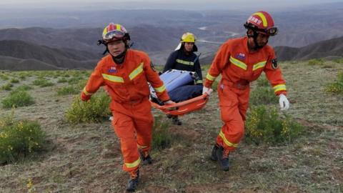 Rescuers carry a stretcher at the site of the ultra-marathon race in Gansu