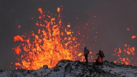 A team of scientists works on the ridge of a volcanic fissure as lava spews during a volcanic eruption, near the town of Grindavik, in the Reykjanes peninsula, southwestern Iceland, 19 December 2023. The Icelandic Meteorological Office (IMO) announced the start of a volcanic fissure eruption near the Sundhnuka crater, north-east of Grindavik, on the night of 18 December, following weeks of intense earthquake activity in the area. The power and seismic activity of the eruption have decreased over time, IMO reported on 19 December, adding that since the eruption began, about 320 earthquakes have been recorded.