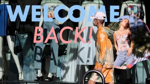 A pedestrian wearing a face mask walks past a storefront in Auckland, New Zealand.