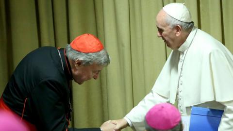 Cardinal Pell, left, bows his head as he sakes the and of Pope Francis in this 2015 photo