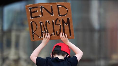 A child hold an 'end racism' sign