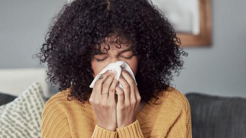 Woman blowing her nose (posed by model)