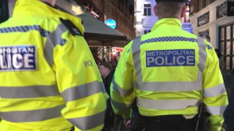 Two uniformed Met officers patrol a street in Soho on a Friday night