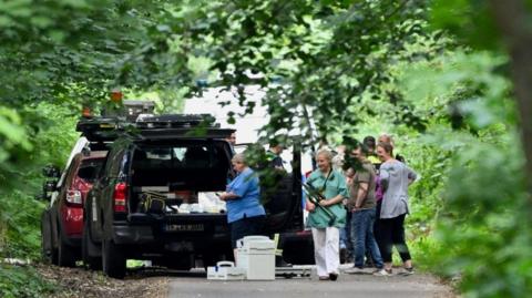 A woman carries a tranquilizer gun as members from the veterinary office search for the suspected lioness after police warned the public that it was on the loose, in Zehlendorf, Berlin, Germany