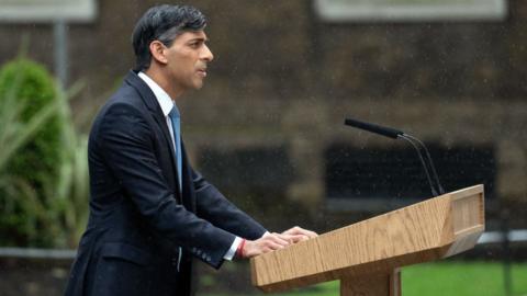 rishi sunak standing at a podium outside number 10 downing street