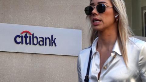 A woman walks by a Citibank logo