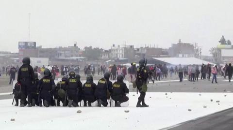 Police on airport runway looking at protesters