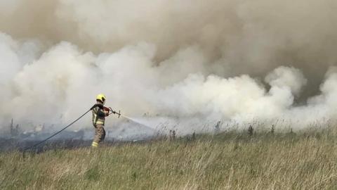 Firefighter tackling field fire near to Rushton, Northamptonshire