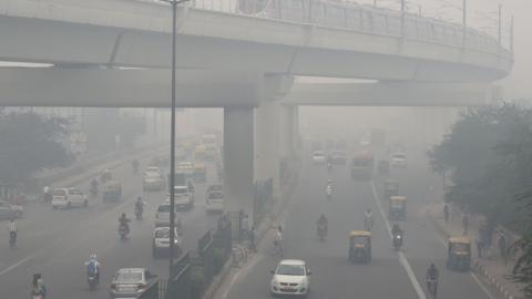 A Delhi Metro train (top) and vehicles drive past amids heavy smog in New Delhi on November 5, 2018.