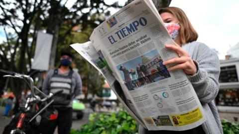 A woman reads a newspaper, with the inauguration of US President Joe Biden on the front page, in Bogota January 2021