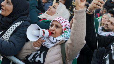 A woman with a microphone at the crowd in central London