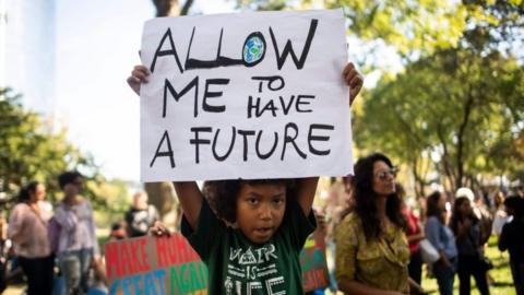 A child holds up a sign reading, "Allow me to have a future" at a climate rally in New York - one of many taking place worldwide on 20 September 2019