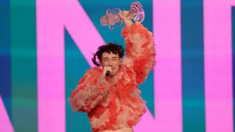 Nemo holds the iconic glass microphone after winning Eurovision 2024