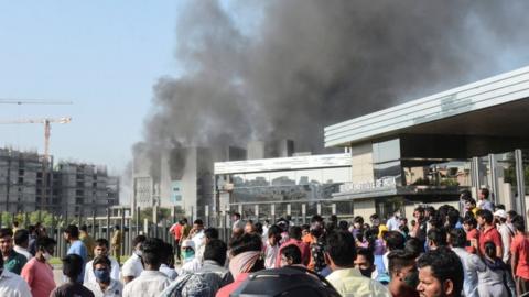 Workers stand outside the site of a deadly fire at the Serum Institute of India's facility in Pune