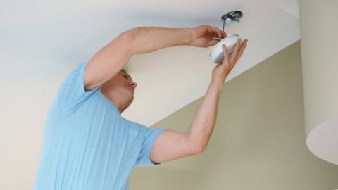 Electrician fitting a smoke alarm