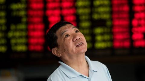 An investor monitors screens showing stock market movements at a brokerage house in Shanghai