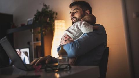 Young father working at home with his baby girl