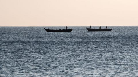 Fishermen work on boats off the coast of North Korea