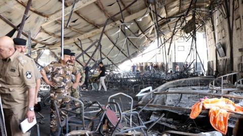 Officials inspect the burned-out interior of the al-Haitham Hall in Qaraqosh, northern Iraq (27 September 2023)