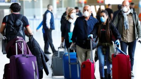 Passengers wear protective masks as they arrive at Frankfurt airport on Tuesday