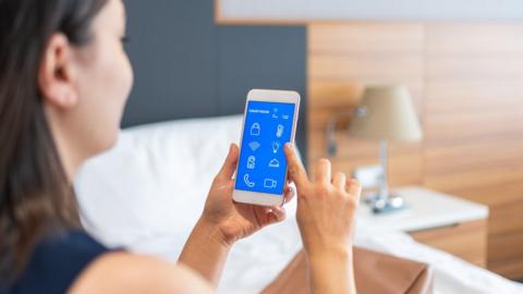 Businesswoman using smart room app in hotel room
