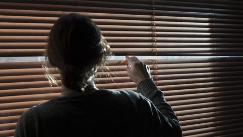 Woman looking through blinds