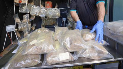 A police worker handles the seized drugs which are packaged in plastic bags