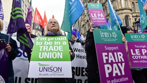 Strikers holding signs outside Belfast city hall