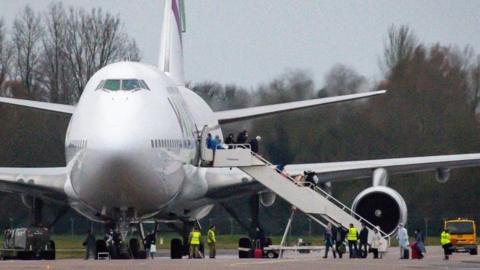 Passengers disembark a plane from Wuhan