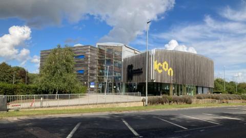 Large concrete and glass building with iCon logo under cloudy blue sky