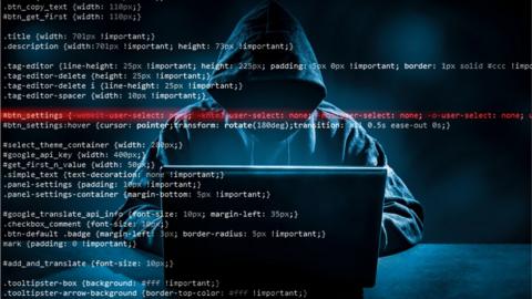 Generic cyber attack image showing hooded hacker at laptop, overlayed with code