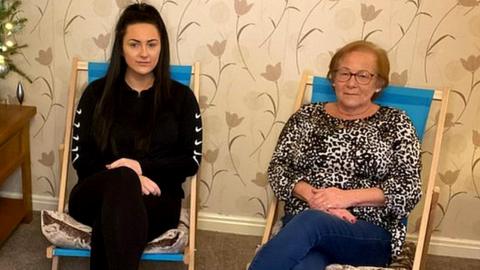 Janet Mellor and her daughter Katie sit on deckchairs in their living room