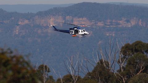 A New South Wales police helicopter retrieves the bodies of a father and son from a walking track where a landslide killed two and injured two others at Wentworth Falls in the Blue Mountains