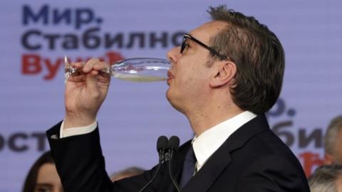 Serbian President Aleksandar Vucic drinks what appears to be champagne after the early results of the general elections in Belgrade, Serbia