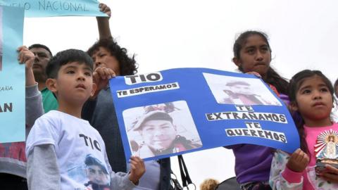 children with poster showing a photo of a man, with lettering in Spanish