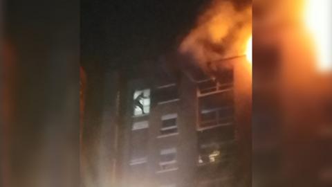 Shadow of man in the window of a burning building