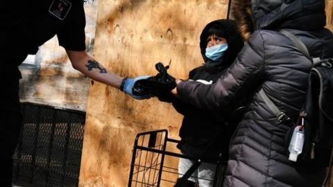 People hand out food at a food distribution site in Harlem that has seen a surge in demand due to the coronavirus outbreak on 7 April 2020