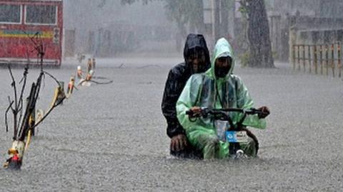 A delivery boy with a electric cycle wades through a flooded street due to heavy rainfall in Mumbai, India, 05 July, 2022.