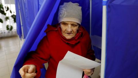 A woman leaves voting booth at polling station during Russia election
