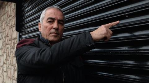 Pat Sheehan pointing at damage caused by a shot fired at a Sinn Fein office