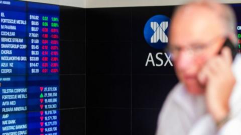 Man in front of ASX market board.